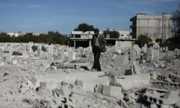 Un homme marche dans un cimetière détruit après des raids aériens dans le village de Deir al-Asafir dans la Goutha orientale, près de Damas, le 25 novembre 2015 