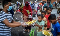 Un bénévole de l'association Mehmankhana distribue des repas à des enfants affectés par la crise du Covid-19, le 26 juillet 2021 à Dacca