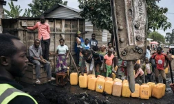 Des habitants de Goma remplissent des bidons d'eau, le 28 mai 2021, pendant que des ouvriers réparent les canalisations rompues par l'éruption du volcan Nyiragongo, en RDCongo