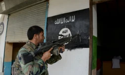 Un soldat de l'armée afghane pointe son arme sur un drapeau du groupe Etat islamique peint sur un mur à Kot, dans l'est de l'Afghanistan, le 26 juillet 2016