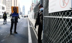 Un manifestant brandit une image de George Floyd devant un membre des forces de l'ordre, le 8 mars 2021, avant le début du procÚs de Derek Chauvin à Minneapolis