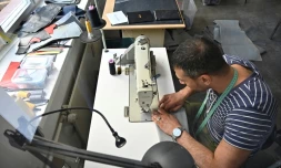 Penché sur sa machine à coudre, le Syrien Khaldoun Alhussain transforme un canot pneumatique en sac ou cabas, dans l'atelier de la petite entreprise mimycri à Berlin