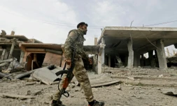 Un combattant des Forces démoctariques syriennes (FDS) passe devant un ancien bâtiment occupé par le groupe jihadiste Etat islamique (EI) dans le village de Hajine dans la province orientale syrienne de Deir Ezzor, le 27 janvier 2019 
