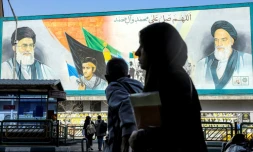 Une femme marche prÚs d'un panneau montrant les ayatollahs Rouhollah Khomeini et Ali Khamenei, le 21 février 2026 à Téhéran
