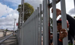 Des migrants d'Amérique centrale espérant pouvoir se rendre aux Etats-Unis regardent à travers les grilles d'un refuge situé près de la fontière américano-mexicaine, à Tijuana au Mexique, le 22 novembre 2018