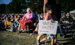 Un petit garçon tient une pancarte "nous sommes unis" lors d'un rassemblement en mémoire des victimes des attaques contre les mosquées de Christchurch, le 24 mars 2019 dans cette ville néo-zélandaise