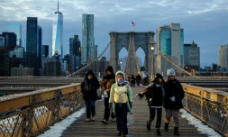 Des passants bravent le froid en traversant le pont de Brooklyn, dans le quartier de Manhattan à New York, le 21 janvier 2026