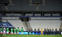 Les joueurs du Paris Saint-Germain et de Saint-Etienne durant la minute d'applaudissements en mémoire des victimes du Covid-19 avant la finale de la Coupe de France de football dans un stade avec peu de spectateurs le 24 juillet 2020 à Saint-Denis