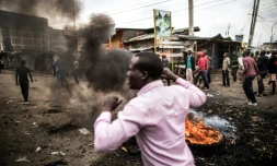 Des habitants marchent près de barricades en flammes dans le bidonville de Mathare à Nairobi, le 9 août 2017. Ils protestent contre les résultats de l'élection présidentielle au Kenya.