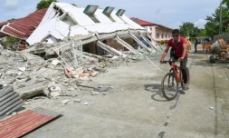 Un homme passe à vélo devant un bâtiment effondré où trois personnes ont été retrouvées mortes après un séisme à Bogo, dans la province de Cebu aux Philippines, le 2 octobre 2025