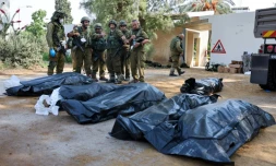 Des soldats israéliens se préparent à retirer les corps des habitants de Kfar Aza, tués lors d'une attaque menée par le Hamas le 7 octobre, à la frontière de la bande de Gaza, le 10 octobre 2023