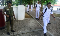 Des jeunes se rendent à l'école à Colombo le 6 mai 2019, sous la surveillance des forces de l'ordre, à la réouverture des écoles fermées aprÚs les attentats qui ont fait plus de 250 morts au Sri Lanka