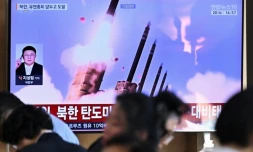 Des personnes sont assises prÚs d'un écran TV diffusant un bulletin d'information avec des images d'archives d'un essai de missile nord-coréen, le 20 septembre 2026 dans une gare de Séoul