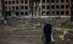 Une femme se tient devant un immeuble détruit aprÚs une attaque des forces russes dans la localité ukrainienne de Vasylkiv, prÚs de Kiev, le 27 février 2022