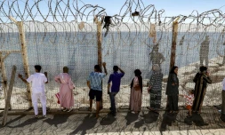 Des personnes attendent derrière une clôture surmontée de barbelés le retour de proches ayant tenté de franchir la frontière pour entrer dans l’enclave espagnole de Ceuta, le 2 août 2026 à Fnideq