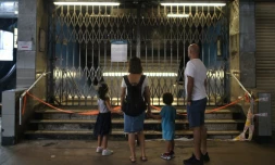 Une famille devant les grilles fermant l'accÚs à une station de métro dans le quartier d'Admiralty, le 6 octobre 2019 à Hong Kong