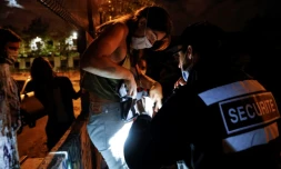 Un officier de sécurité contrÎle les sacs des "teufeurs" qui viennent participer à la free party au bois de Vincennes, le 1er août 2020