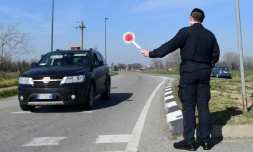 Un policier italien stoppe une voiture à un point de contrôle près de la petite ville de Castiglione d'Adda, au sud-est de Milan, le 24 février 2020.  