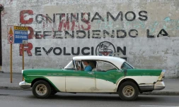 Une voiture passe devant un mur sur lequel s'affiche le slogan "Nous continuons à défendre la Révolution" en référence aux CDR, les Comités de défense de la révolution, le 20 mars 2018 à La Havane, à Cuba