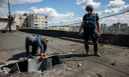 des membres d'une équipe de déminage examinent un engin explosif sur le toit d'un immeuble à Kharkiv, est de l'Ukraine, le 28 avril 2022

