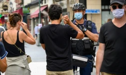 Un policier municipal demande à des passants de porter un masque de protection, le 15 août 2020 à Paris