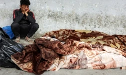 Un Palestinien pleure près de corps de proches tués dans un bombardement israélien à Gaza-ville et couverts de draps à l'hôpital Al-Ahli, le 18 mars 2025