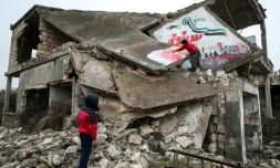 Un homme dessine une colombe de la paix sur une maison détruite et écrit "nous voulons toujours la liberté", le 13 mars 2020 à Binnich, dans la province d'Idleb, dans le nord-ouest de la Syrie