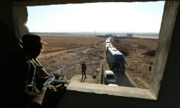 Un membre du groupe jihadiste Hayat Tahrir al-Sham observe un convoi de bus se préparant à évacuer les villes de Foua et Kefraya en Syrie