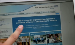 Une femme montre le site Web du NHS (East and North Hertfordshire), informant les utilisateurs d'un problème dans son réseau, à Londres le 12 mai 2017
