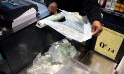 Un employé de supermarché prend un sac plastique à usage unique à Paris, le 28 décembre 2015