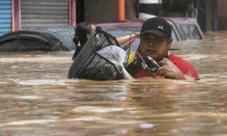 Un habitant porte son vélo en avançant dans une rue inondée après le passage du typhon Vamco, à Marikina City, quartier de Manille, le 12 novembre 2020