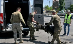 Des policiers spécialisés ukrainiens chargent des débris de missiles russes dans une voiture  le 29 mais 2023 à Kiev