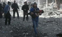 Un secouriste des zones rebelles syriennes en train de secourir un enfant blessé aprÚs de violents bombardement du régime sur la ville insurgée de Hammouriyé, le 19 février 2018