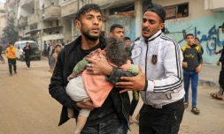 Un homme porte un enfant blessé lors d'un bombardement israélien, le 14 décembre 2023 à Rafah dans la bande de Gaza