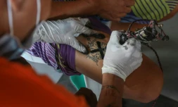 Un tatoueur recouvre d'une croix noire le tatouage qui marque l'appartenance d'un détenu à un gang, le 23 novembre 2020 à la prison de New Bilibid, à Manille, aux Philippines