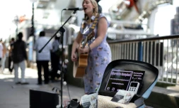 La chanteuse de rue Charlotte Campbell utilise un lecteur de carte bancaire sans contact pour récolter des dons, au pied du London Eye (grande roue) à Londres le 1er septembre 2018