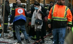 Une femme se fraie un chemin dans  les décombres d'un immeuble où des secouristes interviennent après une frappe aérienne israélienne dans le quartier d'Aïcha Bakkar à Beyrouth, le 11 mars 2026 au Liban