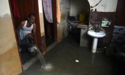 Un habitant de Karachi, dans le sud du Pakistan, écope avec un seau l'eau de son logement inondé par les pluies de mousson, le 26 juillet 2022