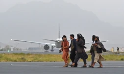 Des combattants talibans passent près d'un avion de Qatar Airways qui doit effectuer un nouveau vol d'évacuation depuis l'aéroport de Kaboul le 10 septembre 2021