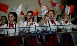 Children wave Chinese flags during the Olympic flame welcoming ceremony in Beijing