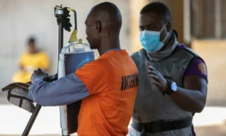 Un membre du personnel médical guide un détenu devant un appareil à rayons X relié à un programme d'intelligence artificielle, à la prison de Maputo, le 6 novembre 2023 au Mozambique