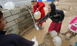 Des enfants remplissent d'eau des jerricans dans le camp de Hammam al-Alil, le 18 mars 2017 en Irak