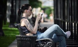 Une femme assise sur un banc utilise son smartphone à Moscou, le 30 juillet 2025