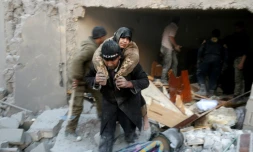 Un secouriste syrien porte une femme sauvée des décombres d'un immeuble après des bombardements dans le quartier d'al-Hamra à Alep, tenu par les rebelles, le 20 novembre 2016 