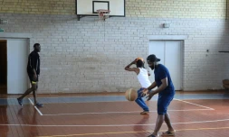 De jeunes migrants jouent au basket dans le gymnase d'une ancienne école transformée en hébergement, à Vydeniai, en Lituanie, le 29 juillet 2021
