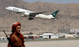 Un combattant taliban monte la garde alors qu'un avion de la compagnie Pakistan International Airlines, premier vol commercial depuis le retour au pouvoir des islamistes le mois dernier, décolle de l'aéroport de Kaboul, le 13 septembre 2021