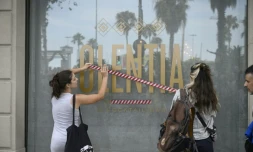Des manifestants installent un ruban sur la vitrine d'un magasin pour protester contre le surtourisme, le 6 juillet 2024 Ă Barcelone