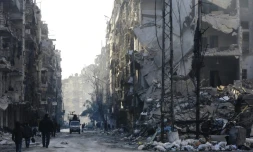 Des habitants des ex-quartiers rebelles d'Alep passent devant des immeubles détruits, le 21 janvier 2017 en Syrie