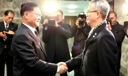 Photo fournie par le ministère de la réunification montrant Kwon Hyok-Bong (g), haut responsable du ministère nord-coréen de la culture, accueillant Lee Woo-Sung du ministère de la culture sud-coréenne, lors de leur rencontre au village frontalier de Panmunjom, dans la zone démilitarisée, le 15 janvier 2018