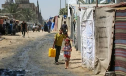 Des enfants déplacés transportent de l'eau jusqu'à leur tente dans un camp de fortune à Deir al-Balah, dans le centre de la bande de Gaza, le 26 août 2024, sur fond de guerre entre Israël et le mouvement palestinien Hamas